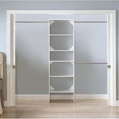 an empty room with a white bookcase and chair next to the open door that leads to another room