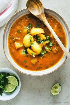 a bowl of soup with potatoes and cilantro on the side next to a spoon