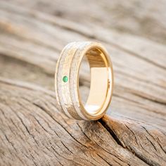 a wooden ring with a green stone in the center on top of a piece of wood