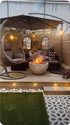 an outdoor living area with a fire pit in the middle and lights on the side