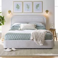 a white bed sitting in a bedroom on top of a wooden floor