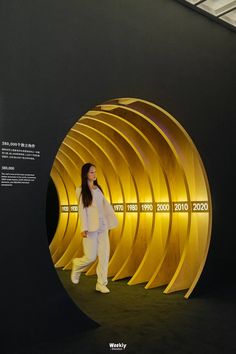 a woman is walking in front of a circular wall