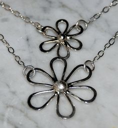 "Delightful Sterling Daisies hand forged from recycled silver are suspended on an 18\" sterling 2 layered chain. The silver petals are hammered for texture and then polished for a high sheen. Large daisy measures 1 1/4\" x 1 1/4\" (30cm x 30cm) and small daisy measures 1\" x 1\" (24 x 24cm). You may choose single small daisy, single large daisy, or the double daisy necklace." Large Daisy, Layered Chain, Daisy Necklace, Recycled Silver, Multi Strand Necklace, Hand Made Jewelry, Nashville Tn, Strand Necklace, Hand Forged