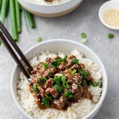 two bowls filled with rice, meat and green onions