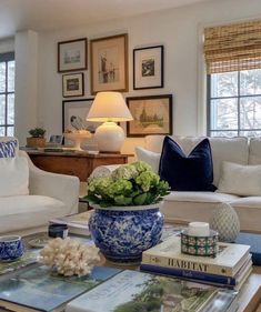 a living room filled with white furniture and blue and white accessories on top of a coffee table