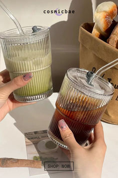 two people holding glasses with drinks in them on a table next to some breads