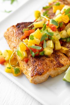 fish with pineapple salsa and lime wedges on a white plate