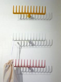 three combs are hanging on the wall next to a bag