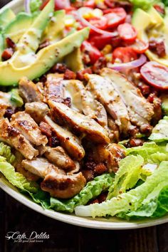 a salad with chicken, lettuce, tomatoes and avocado