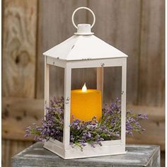 a white lantern filled with purple flowers on top of a table