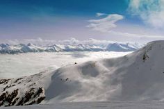 a snowboarder is standing on the top of a snowy mountain