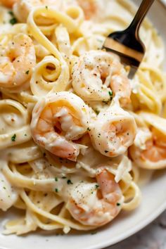 pasta with shrimp and cream sauce in a white bowl on top of a marble table