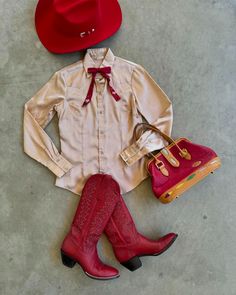 a pair of red cowboy boots sitting on top of a floor next to a white shirt