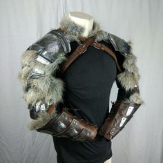 a mannequin dressed in armor and furs on top of a black shirt