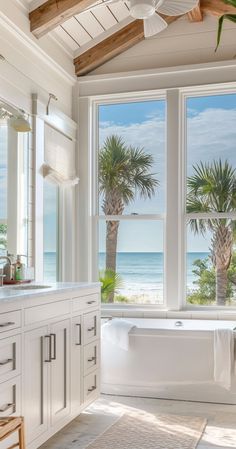 a bath room with a large window and a bath tub next to the ocean in front of it