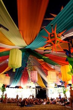 a large group of people sitting in front of a tent with colorful decorations on it