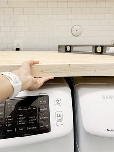 a person holding onto the top of a washing machine