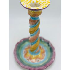 a colorful glass candle holder on top of a saucer with a yellow and blue design