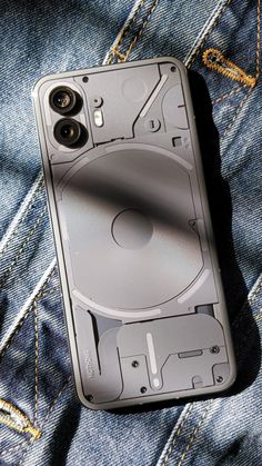 a cell phone sitting on top of a pair of blue jeans with an audio tape recorder in the back