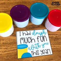 four plastic cups sitting on top of a wooden table next to a sign that says i had dough much fun with you this year