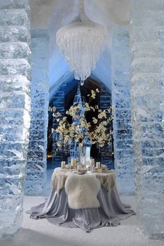 the table is set up in an ice castle like setting with flowers and candles on it