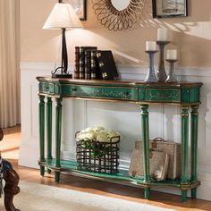 a green console table with flowers and pictures on the wall