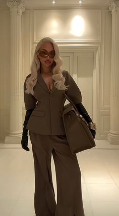 a woman with white hair and glasses is walking down the runway wearing a brown suit