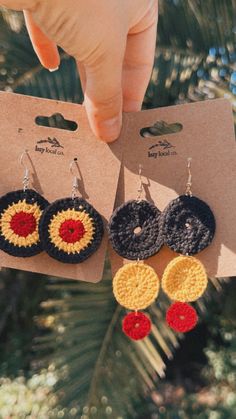 two pairs of crocheted earrings hanging from a card with the same design on it