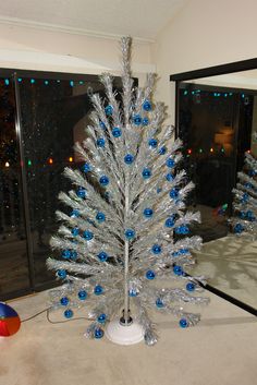 a white christmas tree with blue ornaments on it