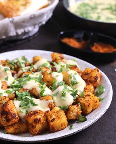 a white plate topped with tater tots covered in cheese and cilantro