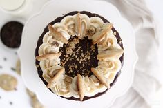 a chocolate cake topped with banana slices and whipped cream on top of a white plate