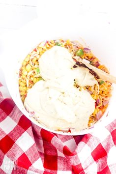 a white bowl filled with food on top of a red and white checkered table cloth