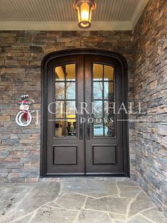 the front entrance to a home with two double doors and brick wall, surrounded by stone pillars