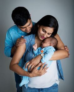 a man and woman holding a baby in their arms