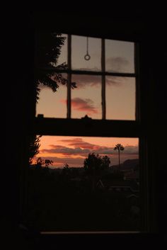 the sun is setting through an open window with a view of palm trees in the distance