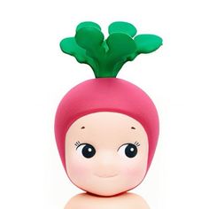 a small doll with a green leaf on top of it's head, sitting in front of a white background