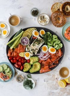 a platter with eggs, salmon, cucumbers, tomatoes, avocado and other foods