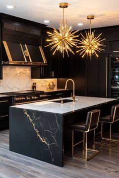 a large kitchen with black cabinets and marble counter tops, gold chandelier above the island