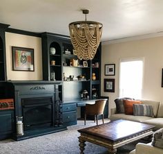 a living room filled with furniture and a chandelier hanging from the ceiling over a fire place