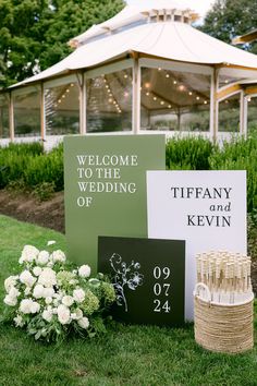 wedding signs and flowers on the grass in front of a gazebo