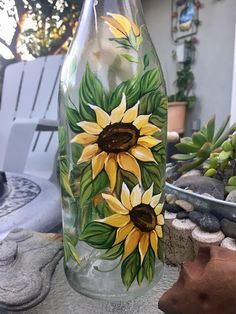 a painted glass bottle sitting on top of a table next to a potted plant