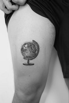 a man's thigh with a small globe tattoo on it