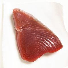 a piece of raw fish sitting on top of a white plate