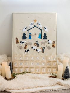 a christmas calendar with candles and decorations on the floor in front of it, surrounded by blankets