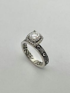 a white gold ring with a diamond in the center and filigrees around the band