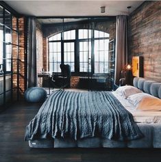 a large bed sitting in the middle of a bedroom next to a window filled with lots of windows