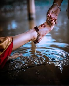 two people holding hands in the water with their feet covered by mud and jewelry on