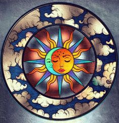 the sun and moon are depicted in this stained glass window with clouds around it,