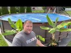 a man holding a potted plant next to an above ground swimming pool in the backyard