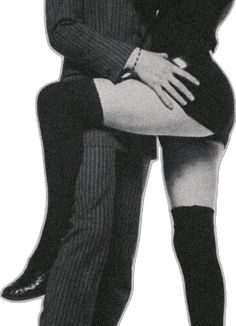 a man in a suit and tie hugging a woman with her legs crossed, both wearing high heeled boots